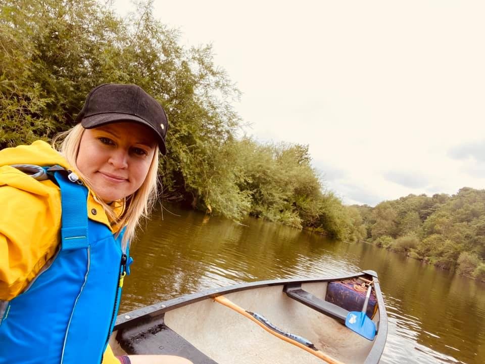Paddler in a yellow cag smiling from the front of a canoe on the Severn