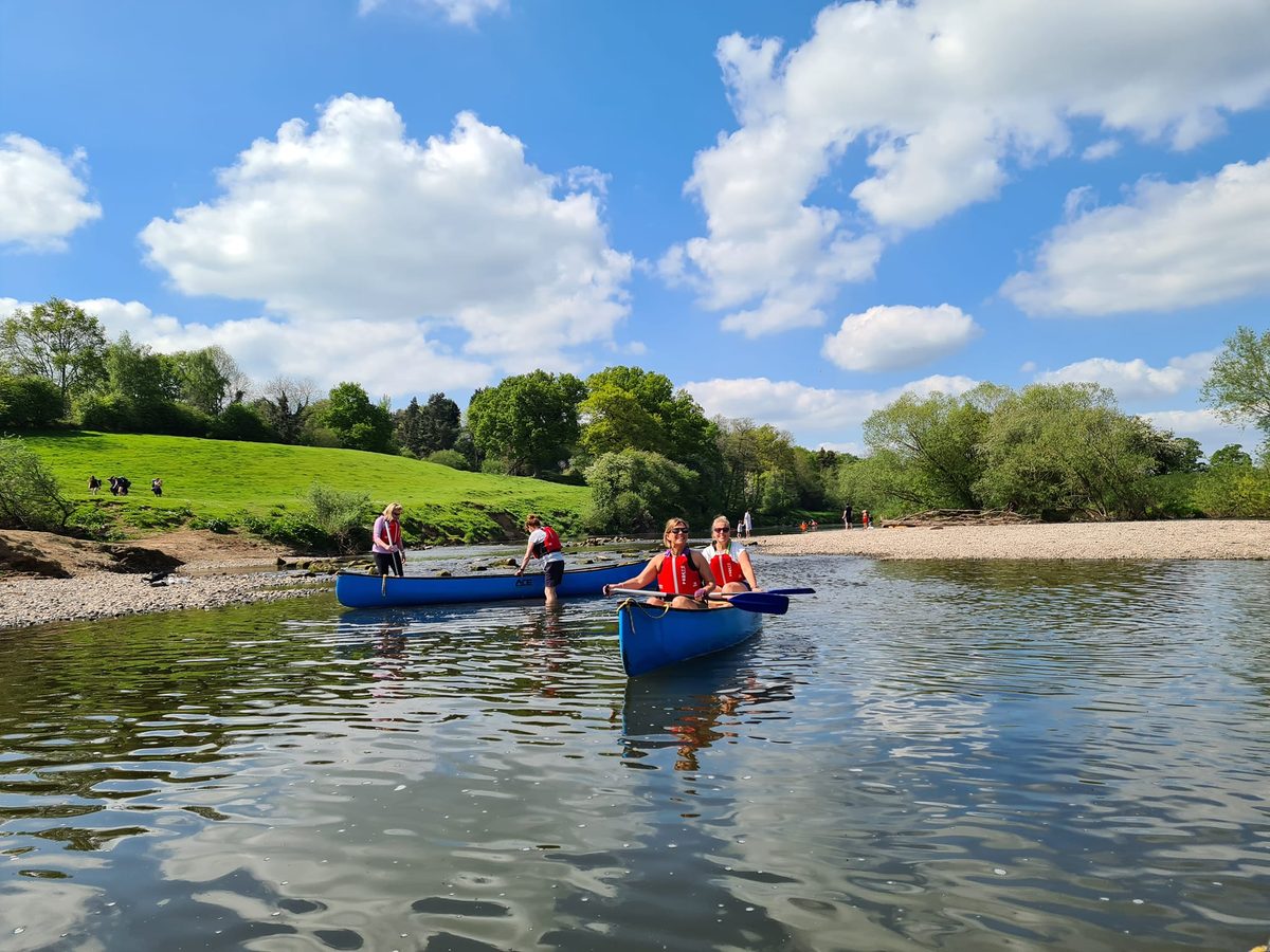 Friends paddling two canoes on the River Severn