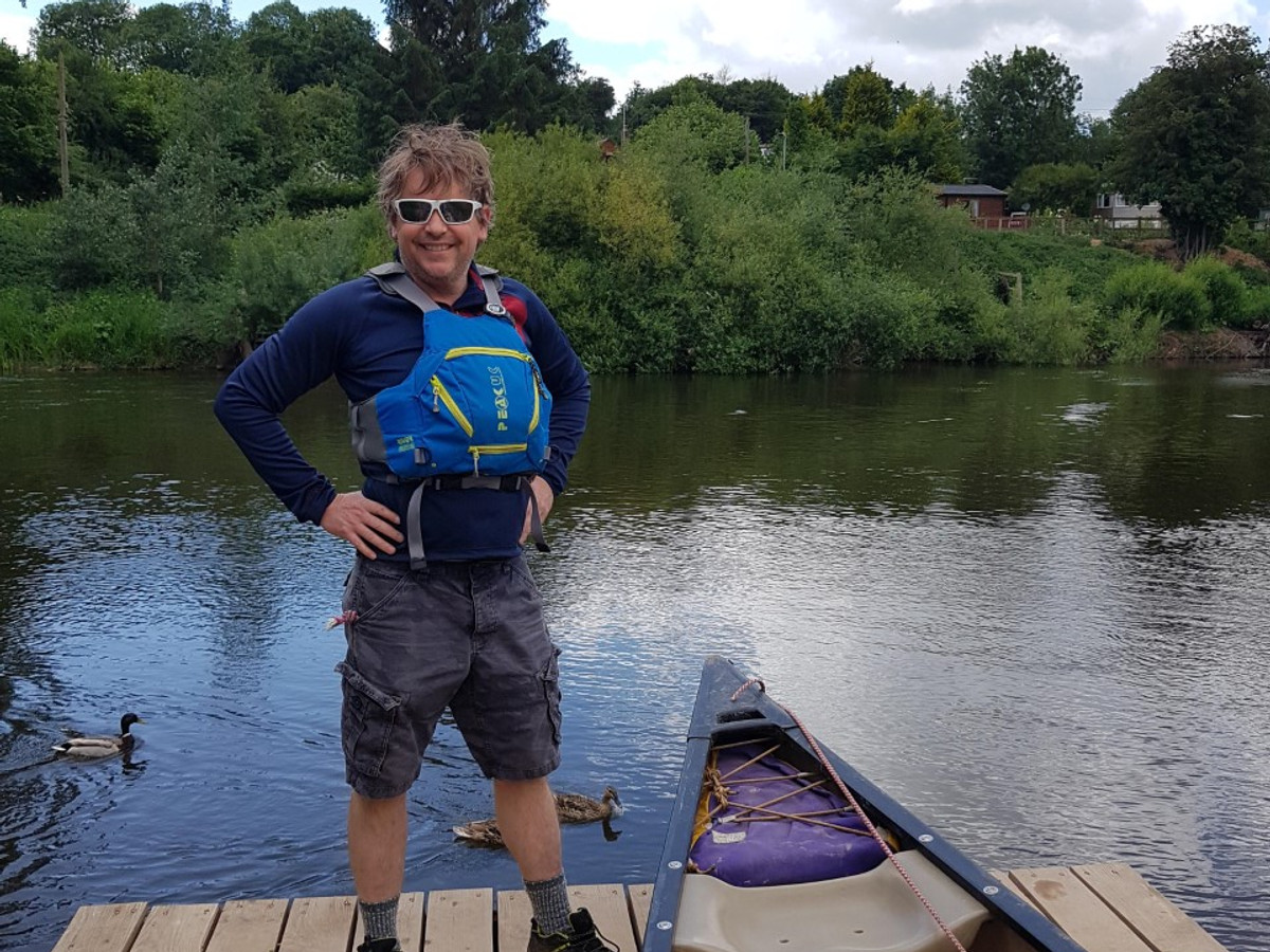 Monty from River Severn Canoes beside a canoe on the riverbank