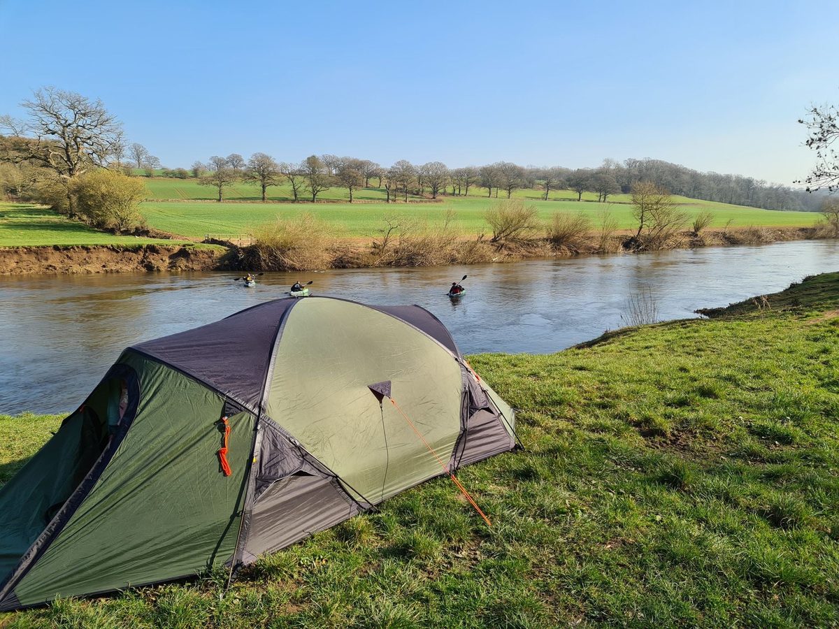 Tent pitched on the riverbank for an overnight canoe camping trip