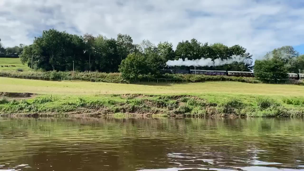 A Severn Valley Railway steam train passing alongside the River Severn, seen from the water